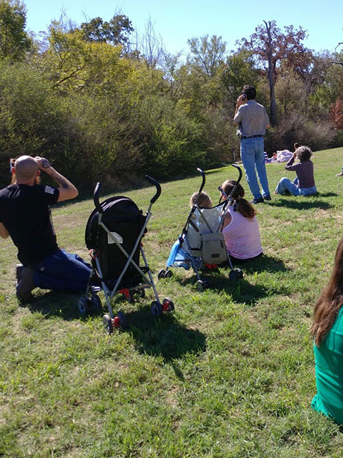 Families sit on lawn of Ringer Library to view eclipse