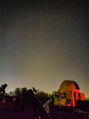 telescopes pointing to sky next to observatory