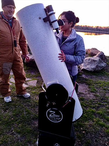 lady looking through Dobsonian telescope with man standing next to her